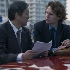 Dwóch mężczyzn w garniturach omawia dokumenty. Czy zastanawiasz się, ile odcinków ma Tokyo Vice?