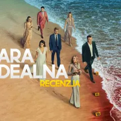 Grupa ludzi na plaży, w tym para idealna serialu. W tle morze i piasek.