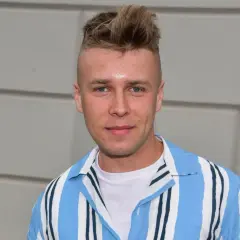 Młody mężczyzna z fryzurą na jeża, w koszuli w paski, wygląda jakby miał zagrać rolę w filmie. Czy Skolim jest aktorem?