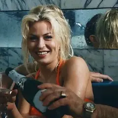 Wspólnik kilera z komedii Machulskiego, uśmiechnięta blondynka nalewa szampana, obok mężczyzna z kieliszkiem.