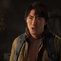 Jesse z The Last of Us w brązowej kurtce i z plecakiem, mówi coś z zaskoczeniem.