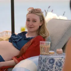 Dakota Fanning, w ciąży, odpoczywa na leżaku przy wodzie. Wygląda na szczęśliwą, jakby czekała na swoje dziecko.