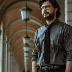 Profesor z Domu z Papieru w okularach i rozpiętej koszuli, planujący kolejny skok.