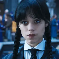 Wednesday Addams w okularach i krawacie, z niecierpliwością czekająca na drugi sezon.