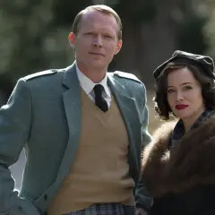 Para, ubrana w tweedową marynarkę i kamizelkę, oraz kobieta w futrzanym kołnierzu i beretce, tworzą scenę jak ze skandalu w brytyjskim stylu.