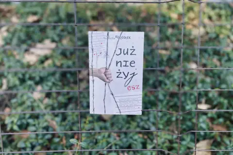 Okładka książki "Już nie żyjesz" Krzysztofa Koziołka, wisząca na płocie. Wstrząsająca historia, która skłania do myślenia, jak zasady przyjemności serial.