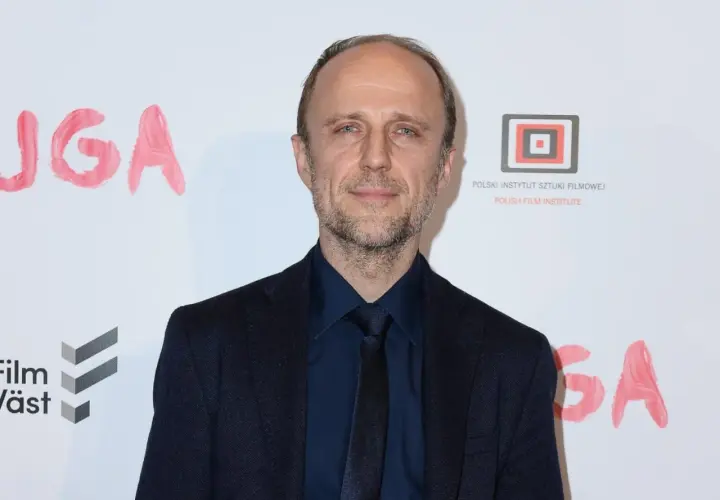 Łukasz Simlat, znany z wielu ról filmowych, na tle napisu "JUGA".