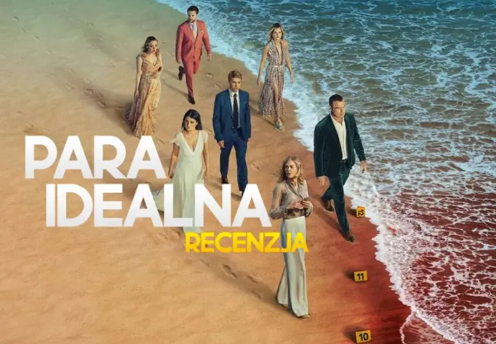 Grupa ludzi na plaży, w tym para idealna serialu. W tle morze i piasek.
