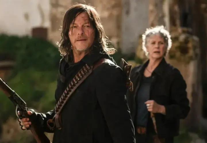 Daryl i Carol, bohaterowie seriali o zombie, przygotowują się do walki. Daryl trzyma strzelbę, a Carol stoi za nim.