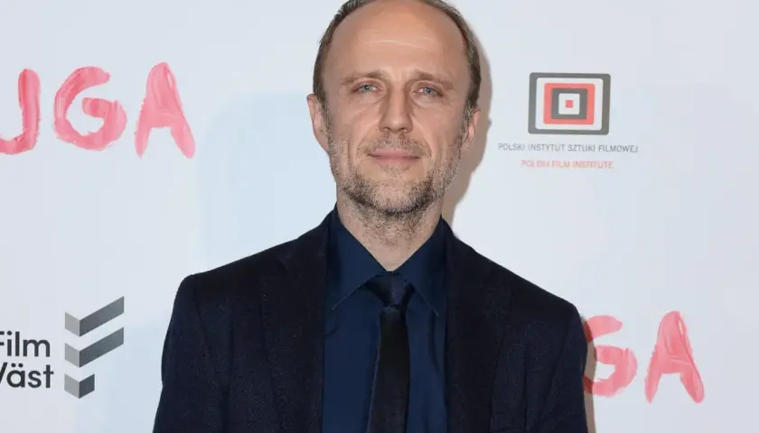 Łukasz Simlat, znany z wielu ról filmowych, na tle napisu "JUGA".