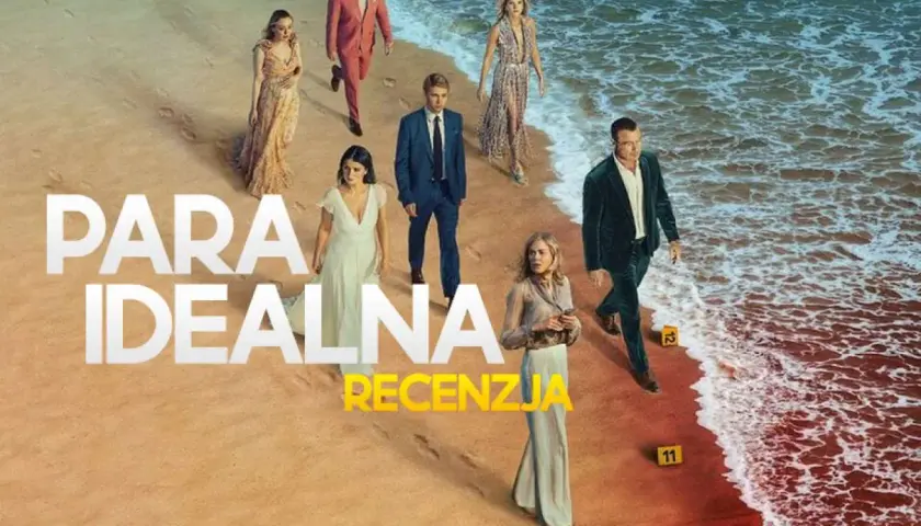 Grupa ludzi na plaży, w tym para idealna serialu. W tle morze i piasek.