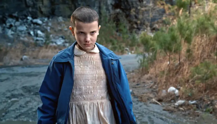 Nastka z Stranger Things, z nosem krwawiącym, stoi na brudnej drodze.