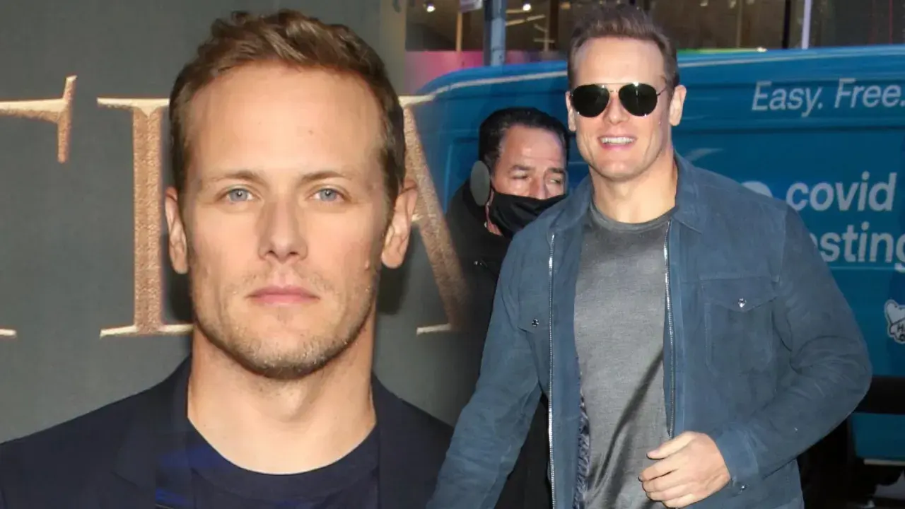 Sam Heughan, znany z roli w Outlander, w okularach przeciwsłonecznych i niebieskiej kurtce. W tle widać fragment logo i napis "covid testing".