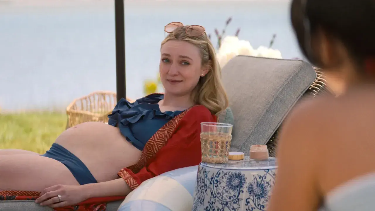 Dakota Fanning, w ciąży, odpoczywa na leżaku przy wodzie. Wygląda na szczęśliwą, jakby czekała na swoje dziecko.