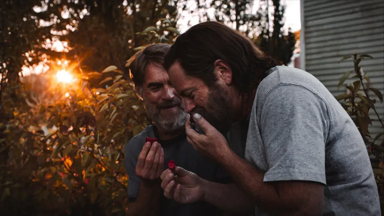 Bill z The Last of Us dzieli się malinami z ukochanym, w ciepłym świetle zachodzącego słońca.