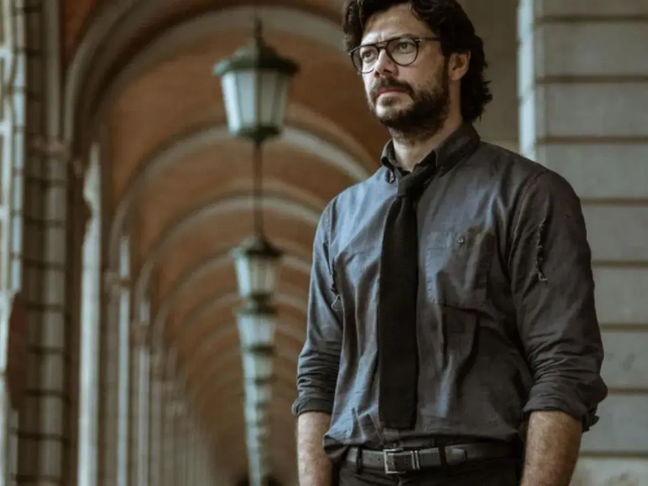 Profesor z Domu z Papieru w okularach i rozpiętej koszuli, planujący kolejny skok.