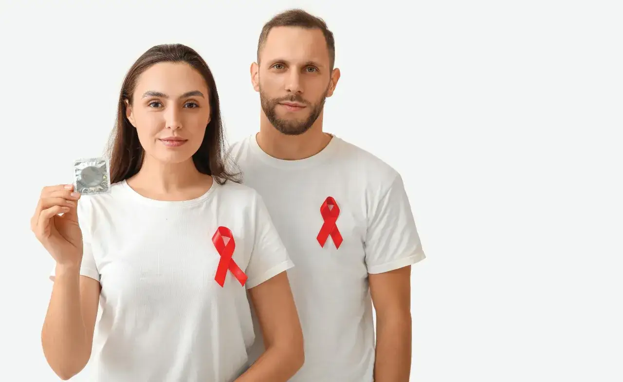 Para młodych ludzi z czerwonymi wstążkami i prezerwatywą, symbolizującą bezpieczne życie seksualne studentek i studentów.
