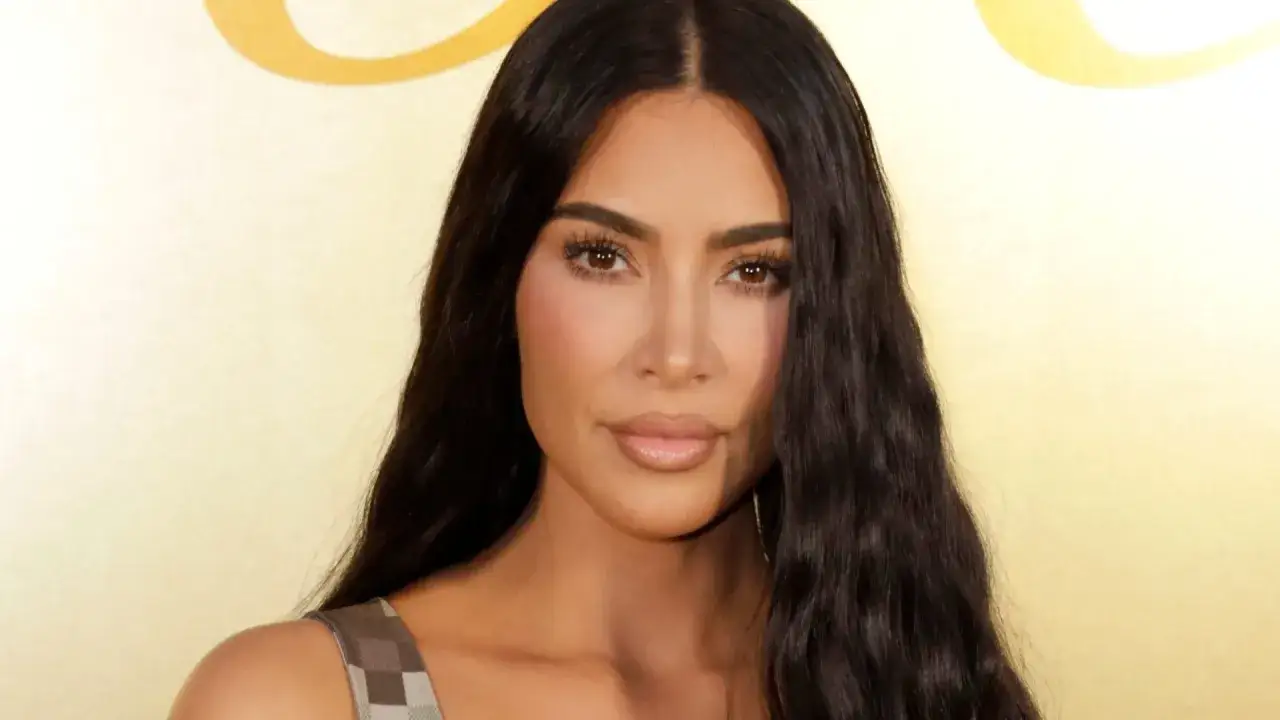 Kim Kardashian w stylizacji z serialu, z długimi, ciemnymi włosami i makijażem.