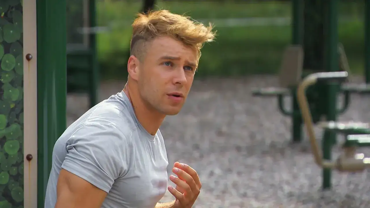 Młody mężczyzna z blond włosami, w szarym t-shircie, siedzi na siłowni plenerowej. Czy Skolim gra jeszcze w barwach szczęścia?