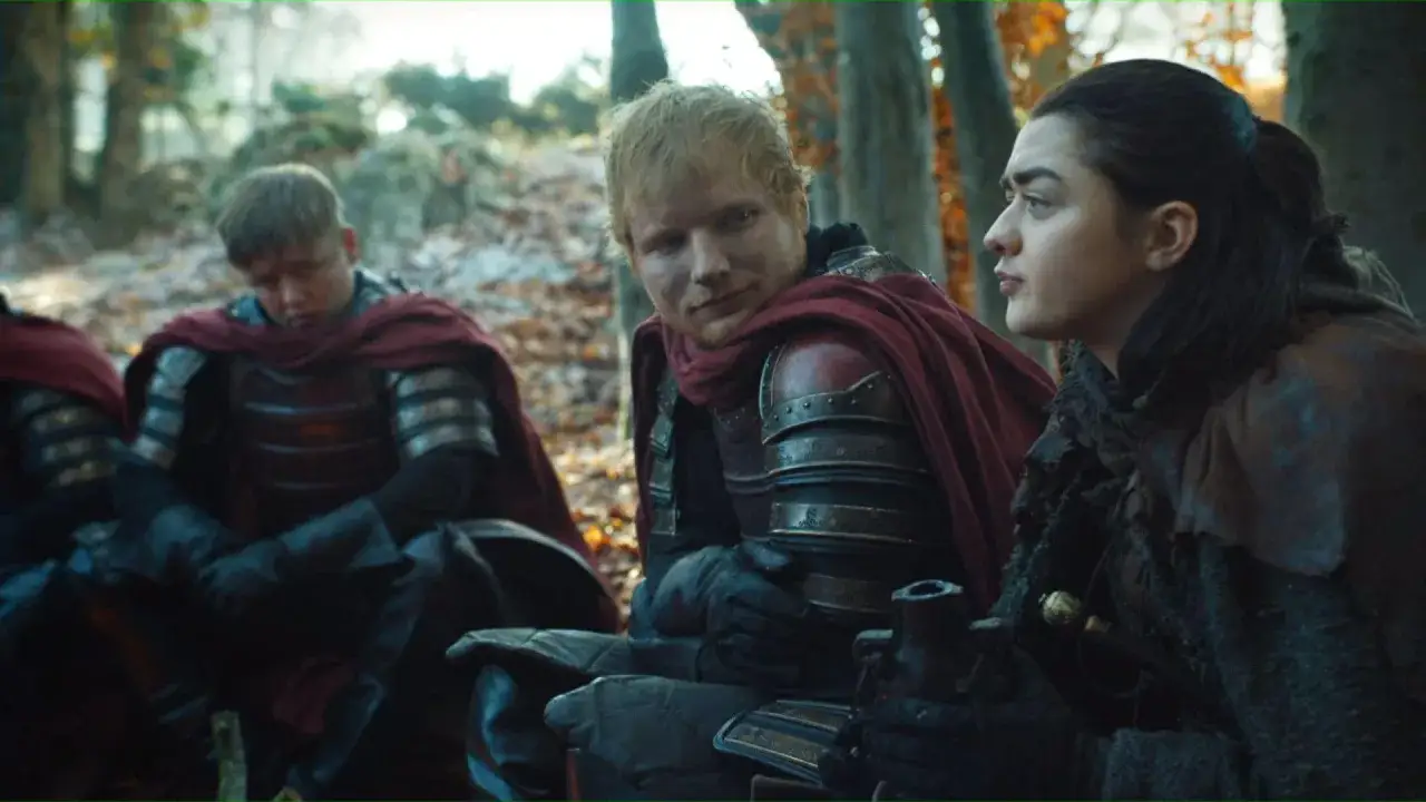 Ed Sheeran w stroju żołnierza z Gry o Tron rozmawia z Aryą Stark w lesie.