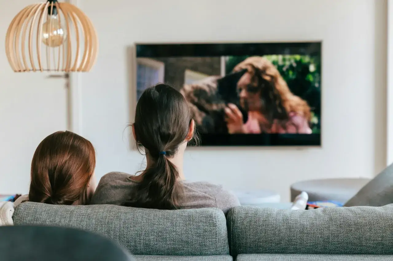 Dwie osoby oglądają film na telewizorze. Szukają wskazówek, jak znaleźć film, którego tytułu nie pamiętają, analizując scenę na ekranie.