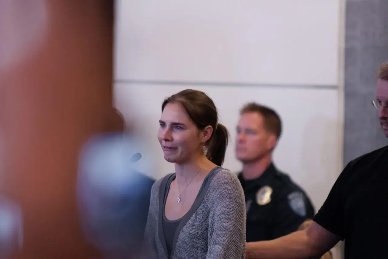 Amanda Knox, w tle policjant. Sprawa Amandy Knox budzi emocje.