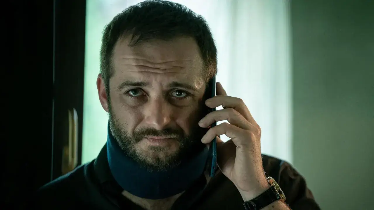 Mężczyzna w kołnierzu ortopedycznym rozmawia przez telefon. To scena z jednego z polskich seriali Canal Plus.