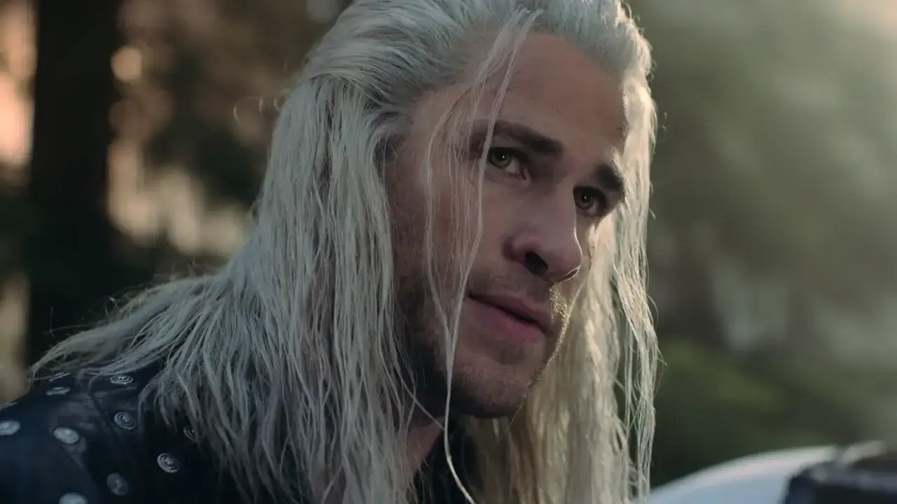 Geralt z Rivii, zamyślony, czeka na kolejny sezon Wiedźmina. Jego białe włosy i przenikliwe spojrzenie budzą emocje.